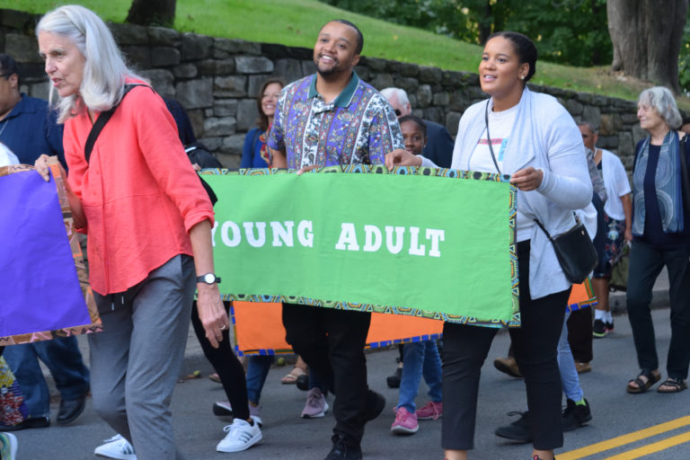 A group of people walking down the street holding signs.