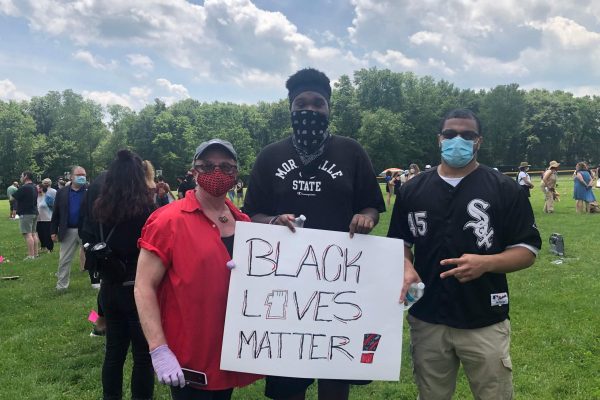 A group of people holding signs and wearing masks.