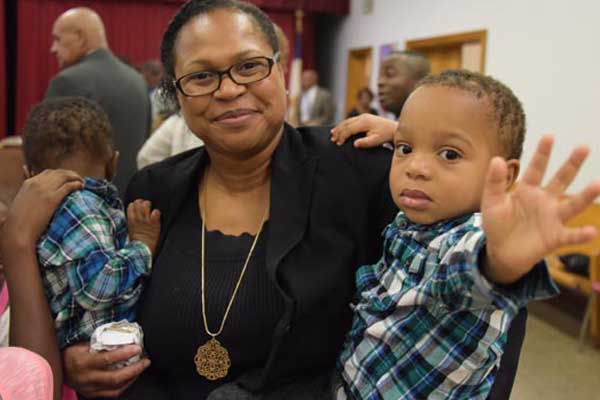 A woman holding two children and smiling for the camera.